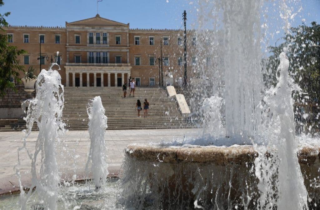 Κρήνη στην πλατεία Συντάγματος στην Αθήνα, με το κτίριο της Βουλής, εν μέσω καύσωνα στην Ελλάδα.
