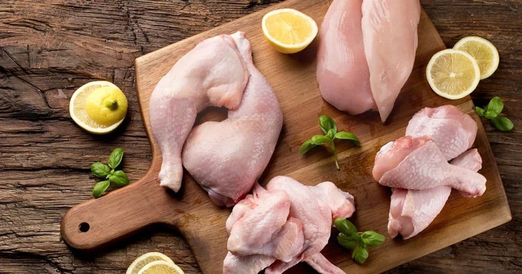 قطع دجاج نيئة متنوعة (أفخاذ، صدور، أجنحة) مع الليمون، توضح أنواع الدجاج المختلفة وأجزائه المتوفرة في السوق المصري.
