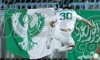 لاعب كرة قدم يرتدي قميصًا أبيض يحمل الرقم 30، يقفز أمام علم النادي المصري الأخضر والأبيض.