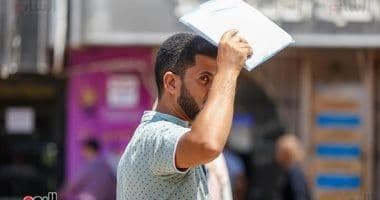 رجل يحمي رأسه من الشمس باستخدام أوراق، يمثل استراتيجيات عملية للتعامل مع الحرارة.