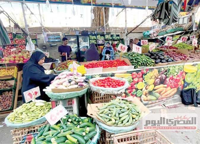 بائعة خضروات في سوق مزدحم، تعكس الاقتصاد الأخضر وتأثير أسعار الخضروات على سبل العيش.