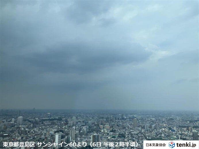 東京の都市上空に広がる暗い雨雲と、激しい雨の予兆