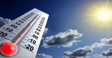 مقياس حرارة كبير يظهر درجات الحرارة تحت سماء زرقاء مع شمس وغيوم، يمثل التنبؤات الجوية اليومية.