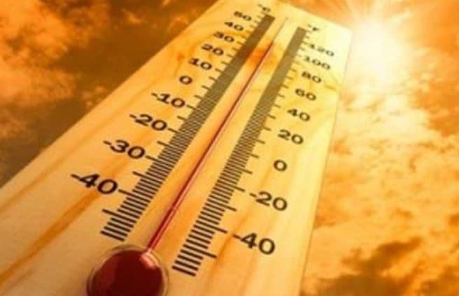 مقياس حرارة خشبي يشير إلى درجات حرارة عالية جداً تحت سماء حارة، يرمز إلى الاحترار العالمي وتغير المناخ.