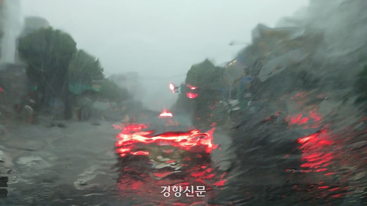 폭우가 쏟아지는 도로 위 차량의 모습, 한국 기상청 날씨 누리의 극한 호우 경보 및 재난 대비 역할 강조.