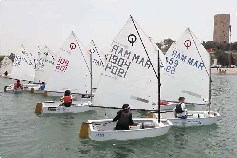 قوارب شراعية صغيرة تبحر في المياه قبالة ساحل الرباط، تبرز التأثير البحري على المناخ المغربي