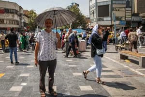 مردی در خیابانهای ایران با چتر در برابر گرمای شدید خورشید، نمادی از افزایش دما و تغییرات اقلیمی