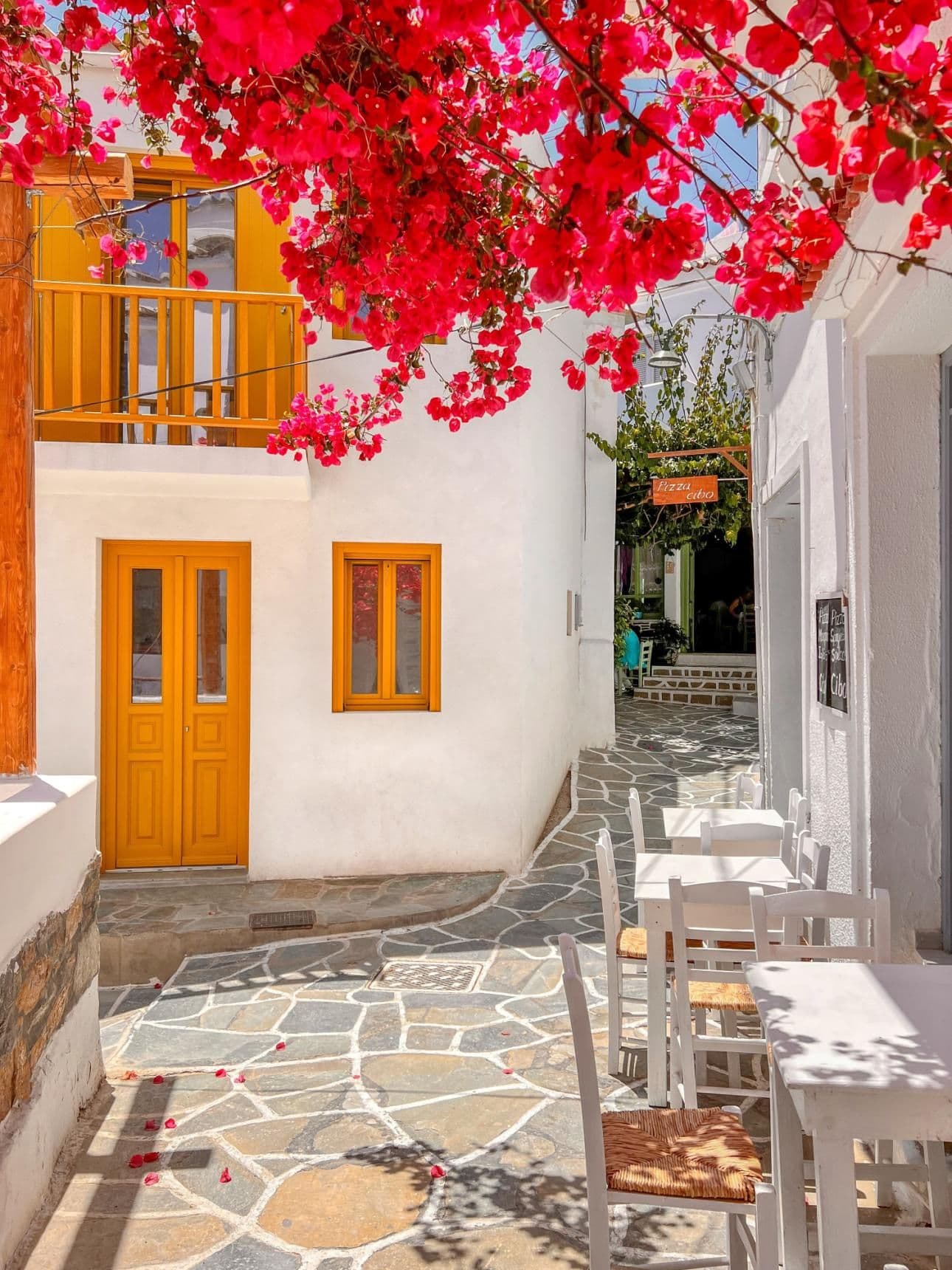 A charming, quiet street in a Kythnos village with white buildings and vibrant bougainvillea, reflecting the island's slow living.