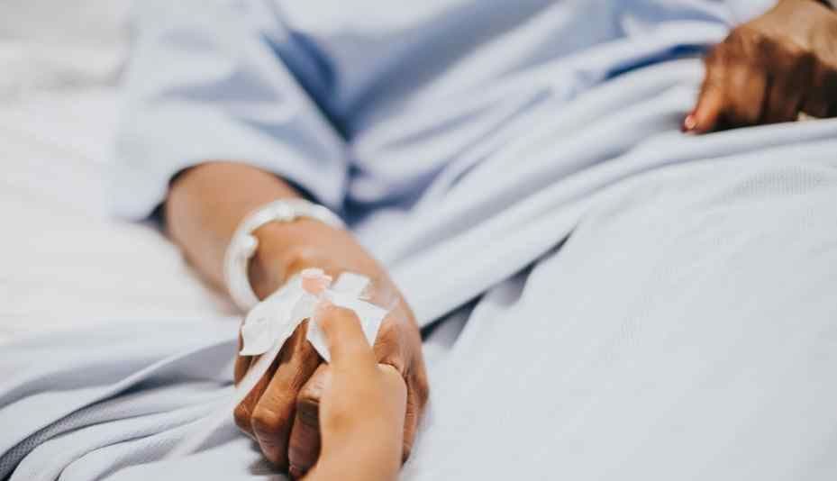 A child's hand holding an adult's hand with an IV drip, illustrating the unseen health toll and vulnerability to extreme heat.