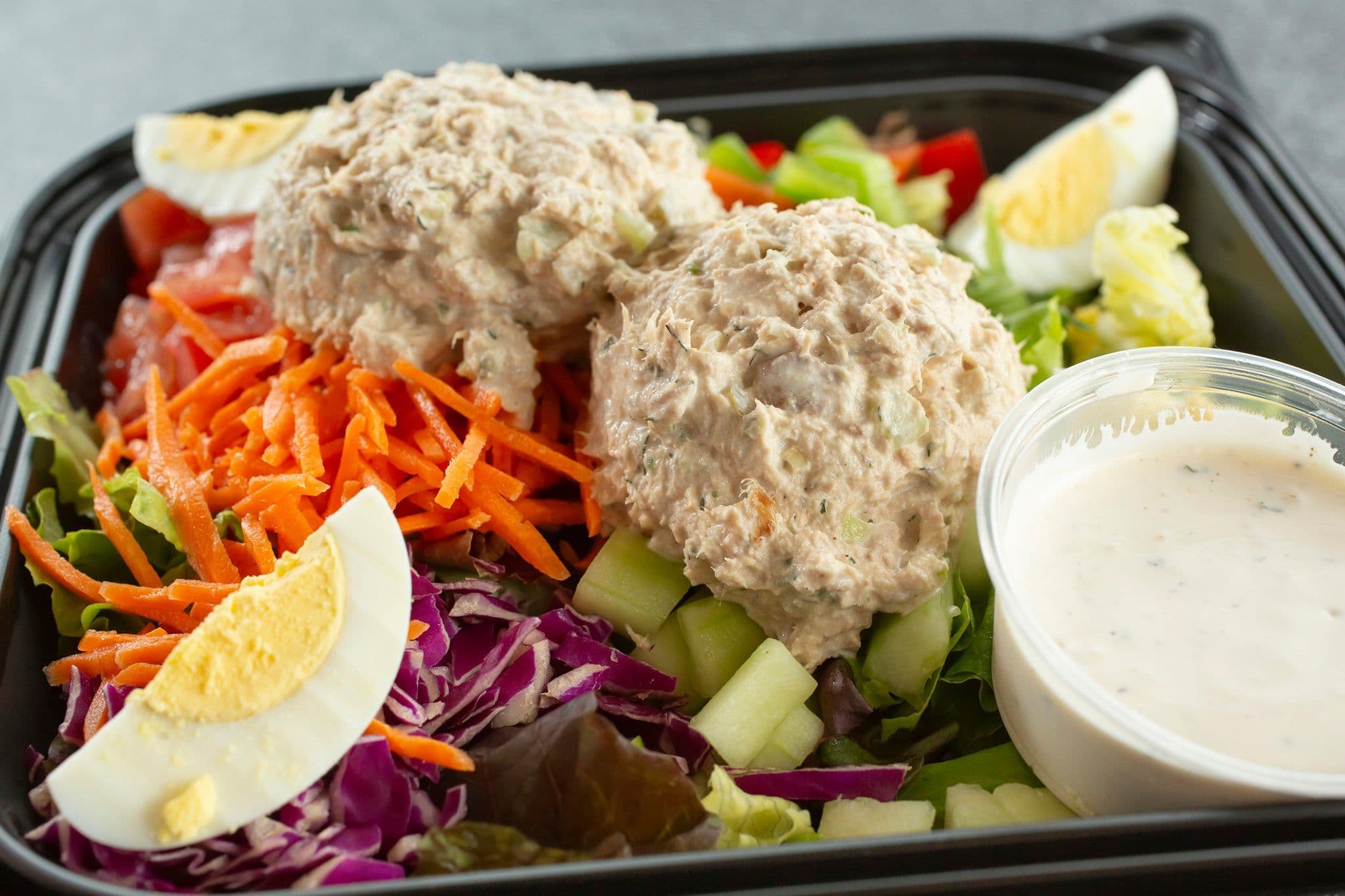 A close-up of tuna salad with mixed greens and vegetables in a takeout container, representing the recalled products.