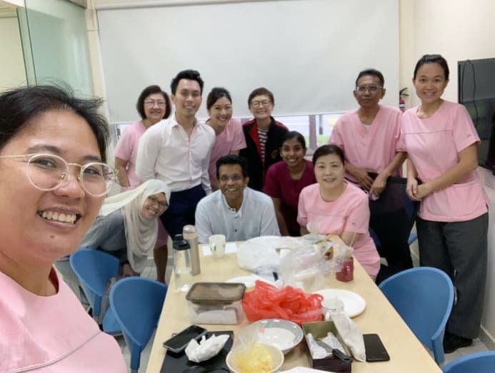A diverse group of professionals smiling in a modern office setting, representing Singapore's skilled workforce and its focus on human capital development and innovation.