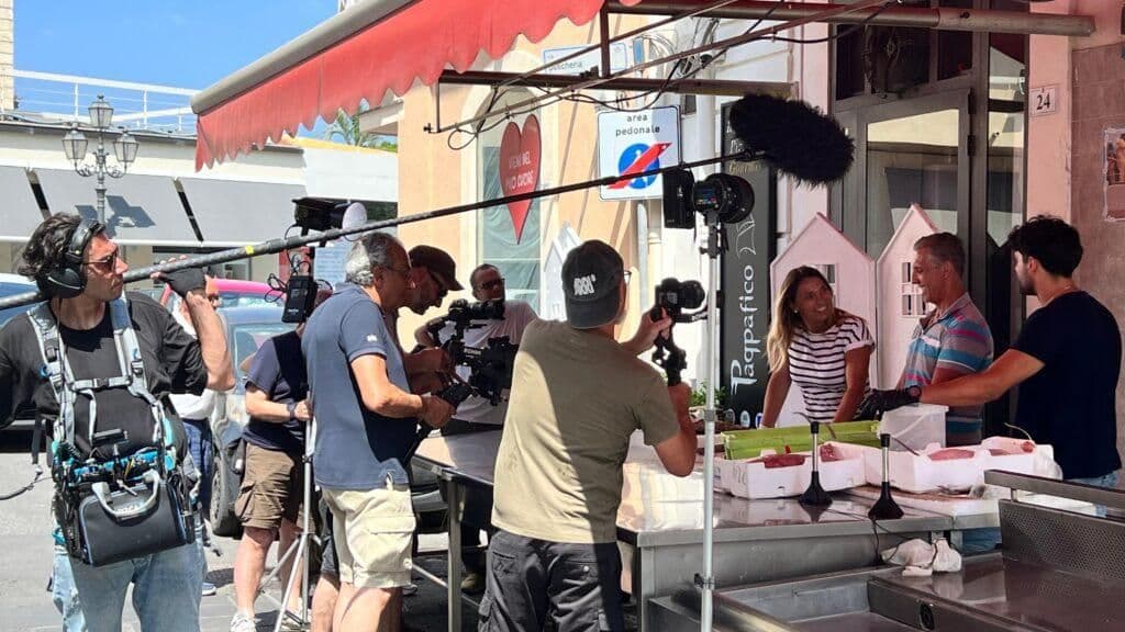 A film crew captures the vibrant scene at a Milazzo fish market, highlighting the region's rich maritime heritage and fresh seafood.