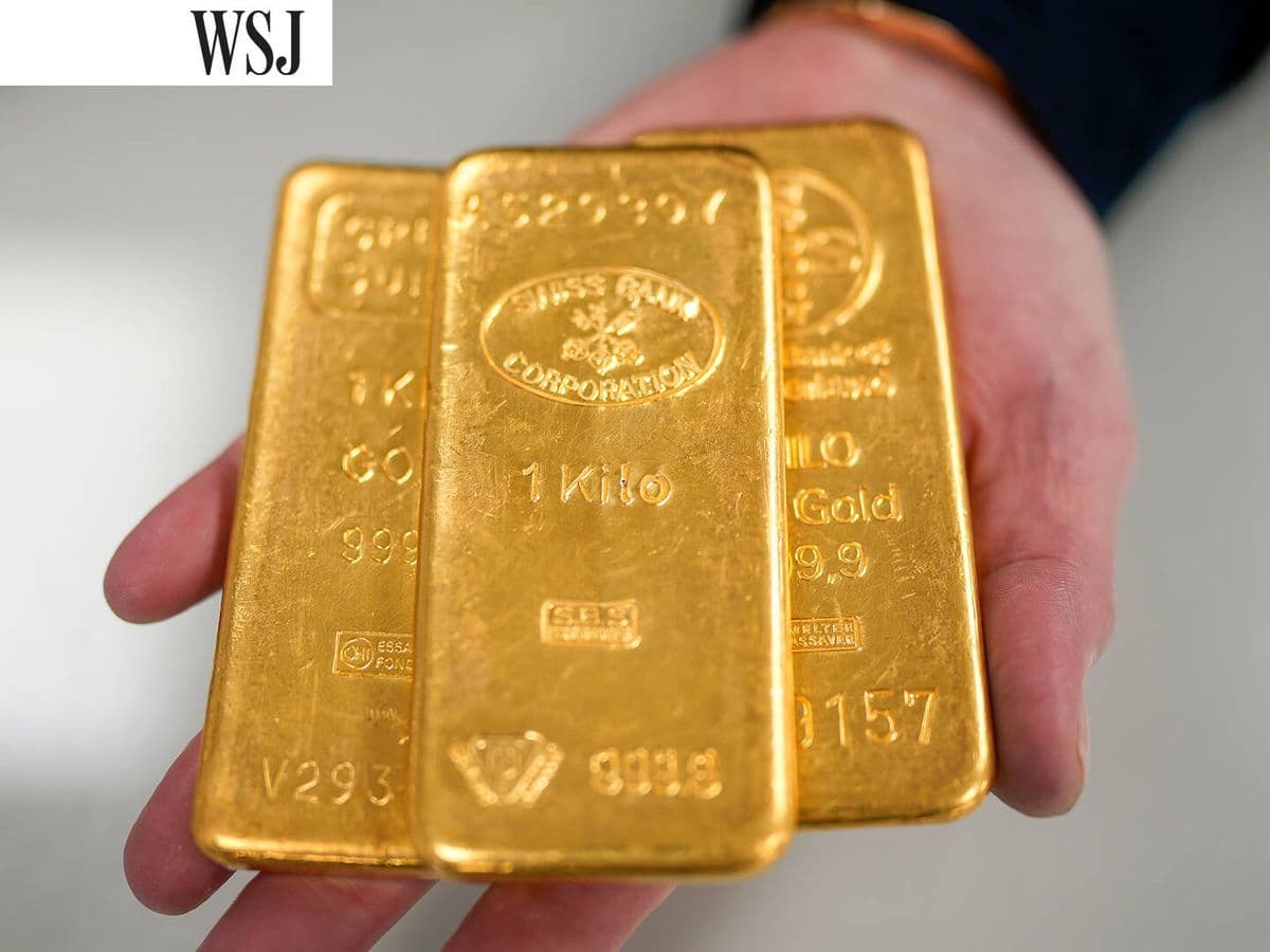 A hand holding three one-kilo gold bars, symbolizing gold's enduring value and its role as a global financial anchor.