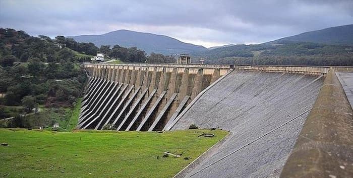 A large dam structure in a green landscape under a cloudy sky, symbolizing water resource management in Tunisia.