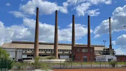 A large factory with multiple tall chimneys under a blue sky, symbolizing the industrial assets acquired by Sanjeev Gupta's GFG Alliance.
