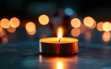 A lit candle, symbolizing the human cost and loss of a railway worker's life.