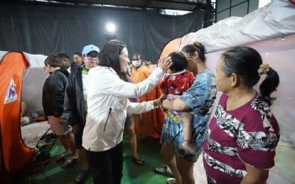 A local government official interacting with residents in an evacuation center, showcasing disaster response and preparedness efforts.