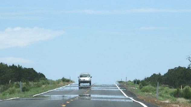 A long, straight road with visible heat haze, symbolizing the intense and enduring heat affecting Italy's climate.