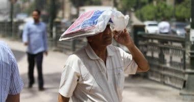 A man shielding his head with a makeshift cover while walking in intense heat, symbolizing the severe impact of a heatwave.