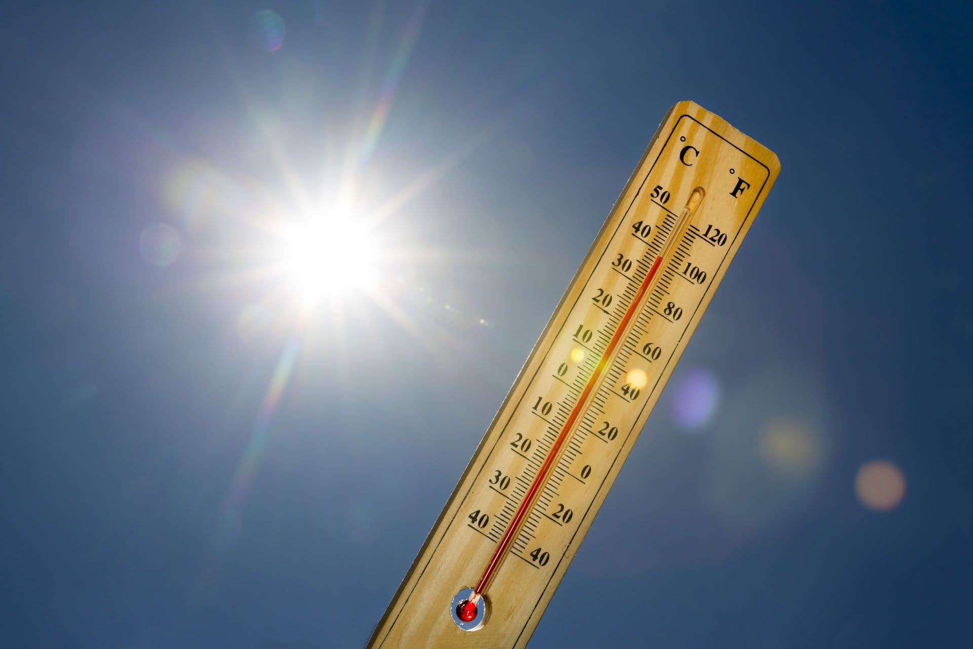 A mercury thermometer showing high temperatures against a bright sunny sky, representing the intense 'real feel' heat.