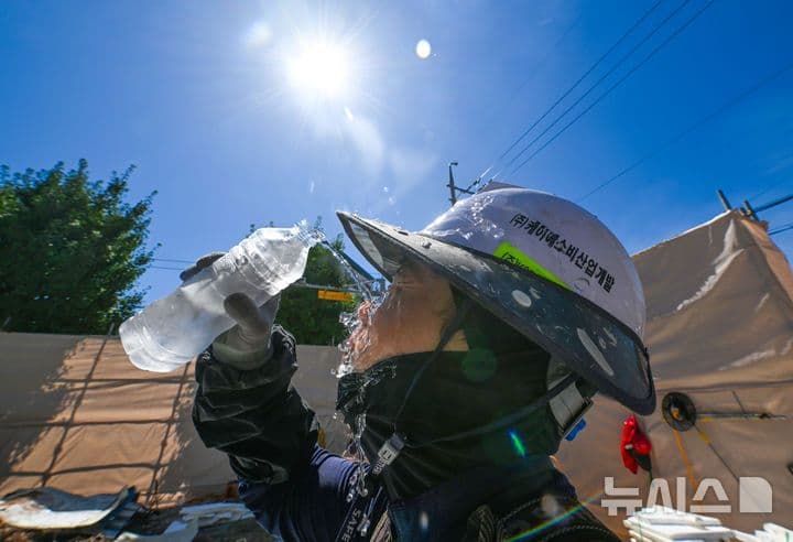 A person pours water over their face under the scorching Gwangju sun, battling the record summer heat.