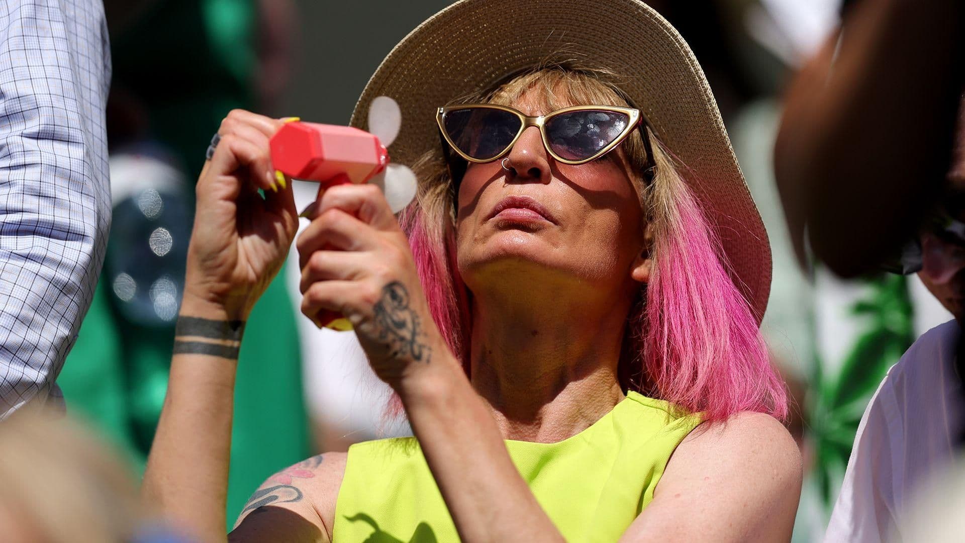 A person using a portable fan to cool down on a hot day, symbolizing the personal and economic costs of UK hot spells.