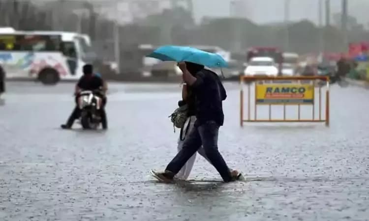 A person walks through a waterlogged street during heavy monsoon rain in Tamil Nadu, illustrating the impact of current weather alerts and forecasts.