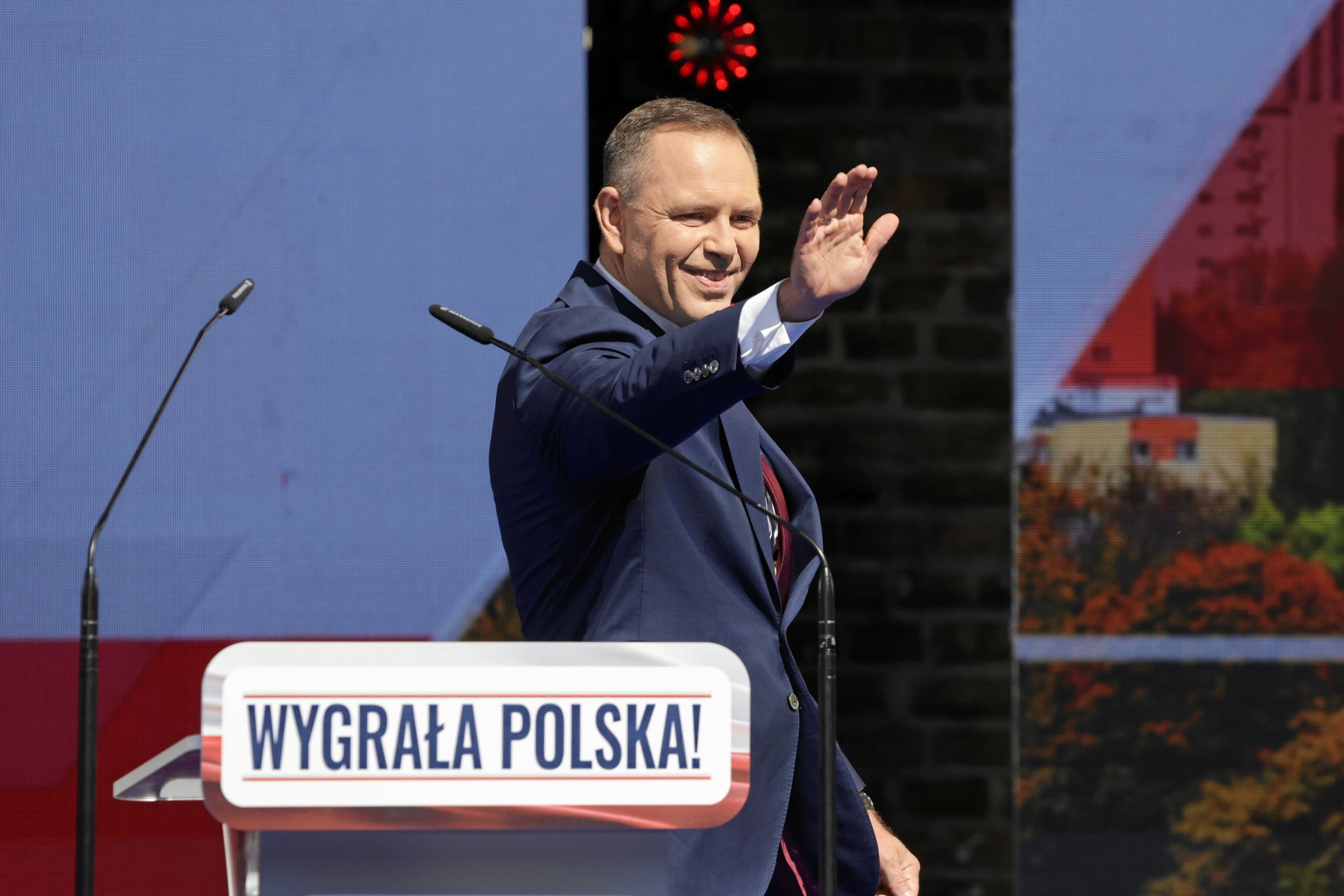 A politician waving to a crowd with a 'Poland Won!' sign, representing Onet's commitment to informed citizenship and public participation.