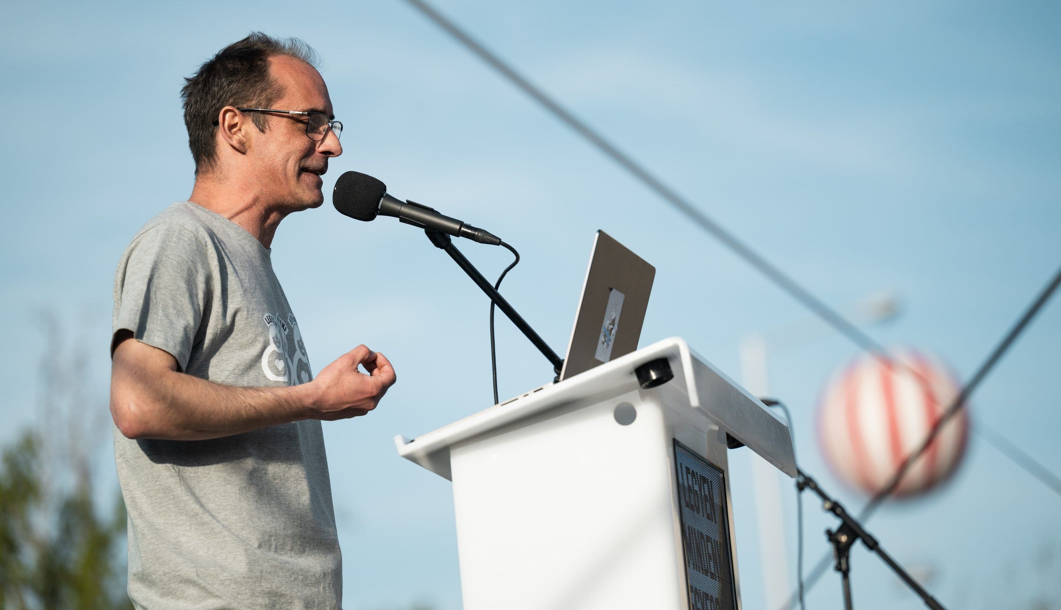 A scientist or expert speaking at a podium with a microphone and laptop, discussing climate change and ecological impacts.