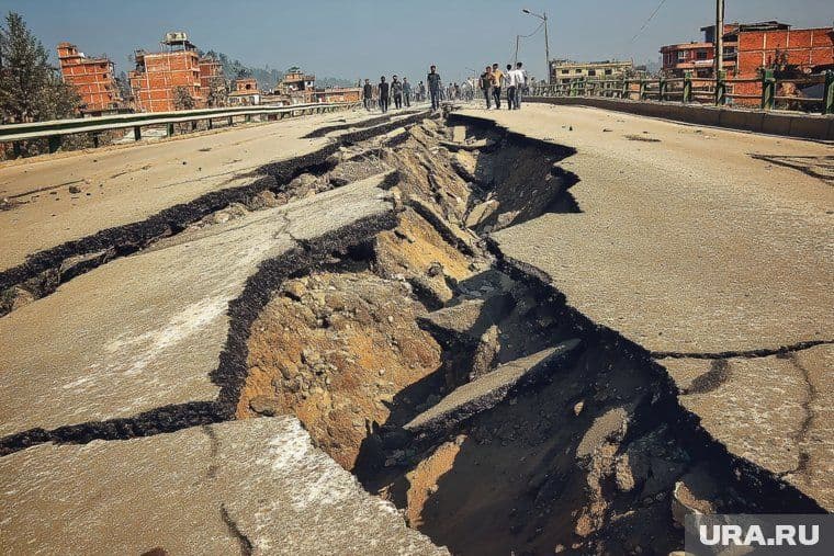 A severely cracked and broken highway with a deep chasm, symbolizing ground instability and geological precursors.