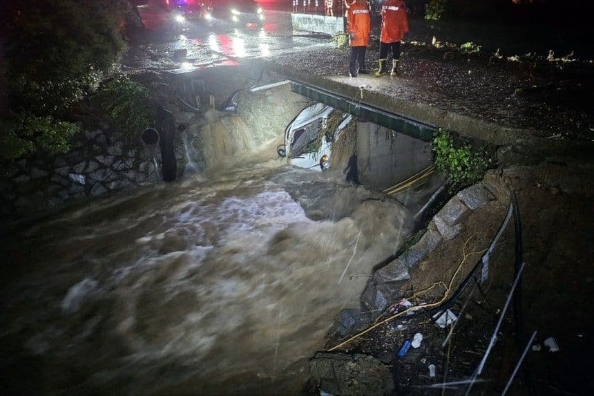 A severely flooded road and overflowing river at night, highlighting the critical need for flood safety during Korea's summer downpours.