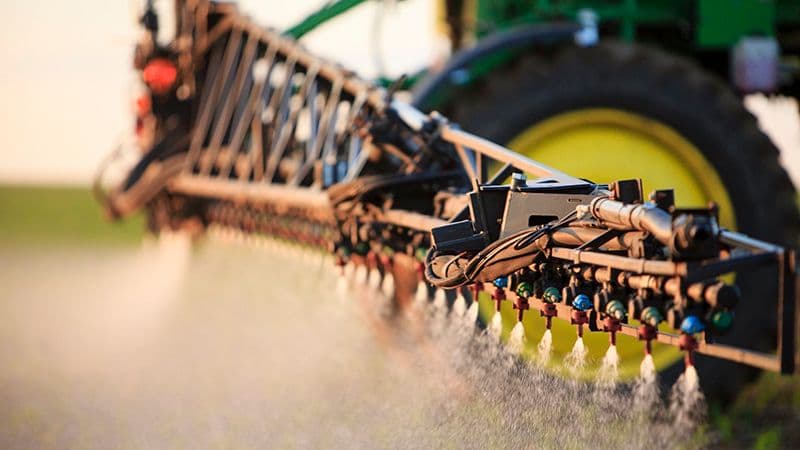 A tractor applying crop inputs in a field, illustrating the practical use of fertilizers in agricultural production.