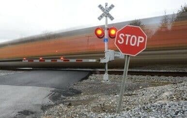 A train passing a railroad crossing with active warning lights and a stop sign, representing railway safety protocols.
