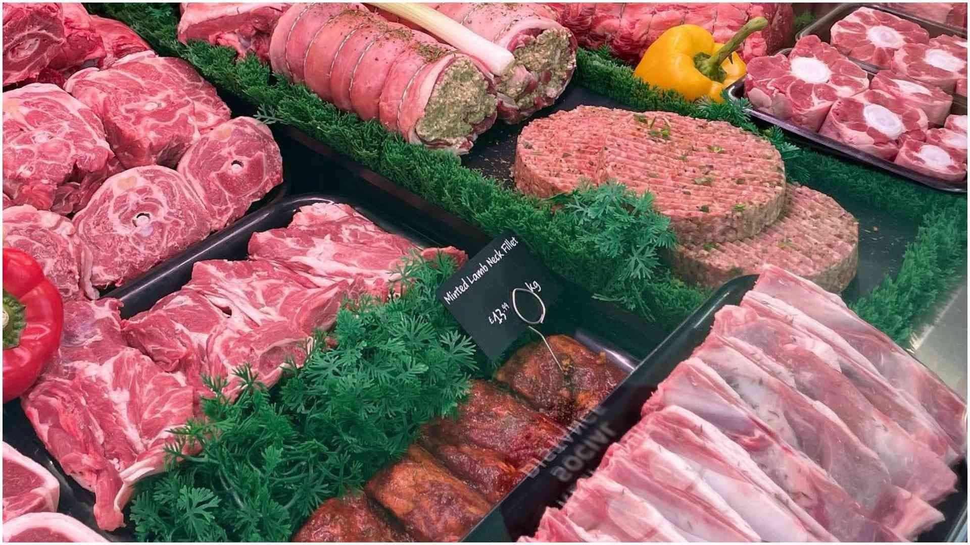 A variety of raw meat products displayed in a refrigerated supermarket display case.