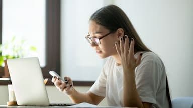 A woman looking surprised or concerned while checking her phone, symbolizing the unexpected jolt of inflation data.