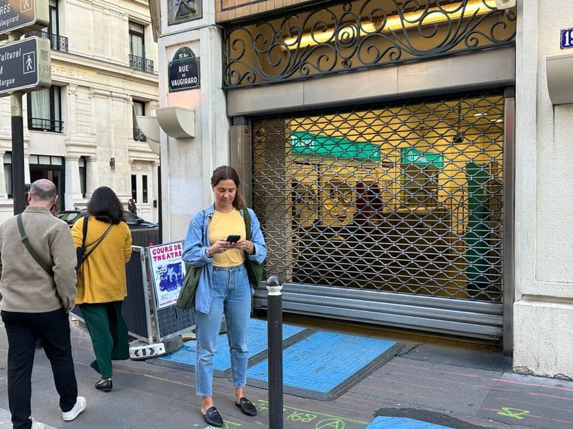 A woman stands before a closed metro station in Paris, illustrating the media's narrative of minimal impact and a 'non-event' protest.