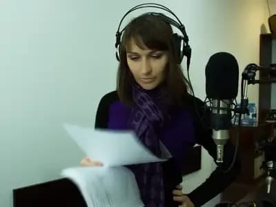 A woman wearing headphones and looking at papers, possibly a meteorologist or broadcaster, representing weather updates.