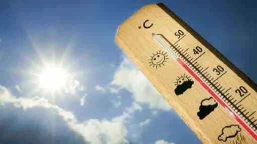A wooden thermometer showing high temperatures under a bright sun and blue sky, illustrating the intensified heatwave in Egypt.