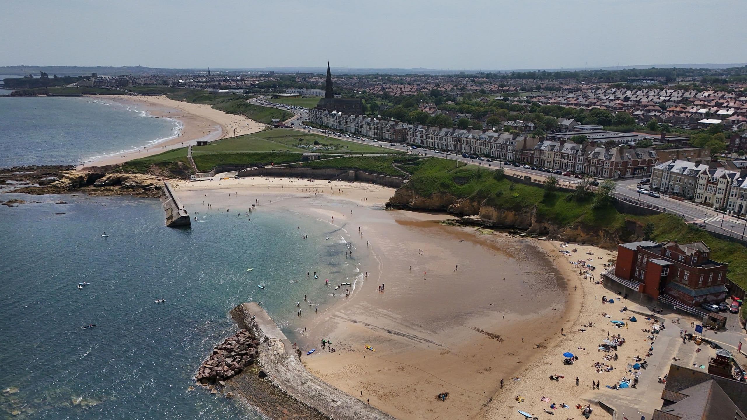 Aerial view of a crowded British beach on a sunny day, symbolizing summer heatwave aspirations.