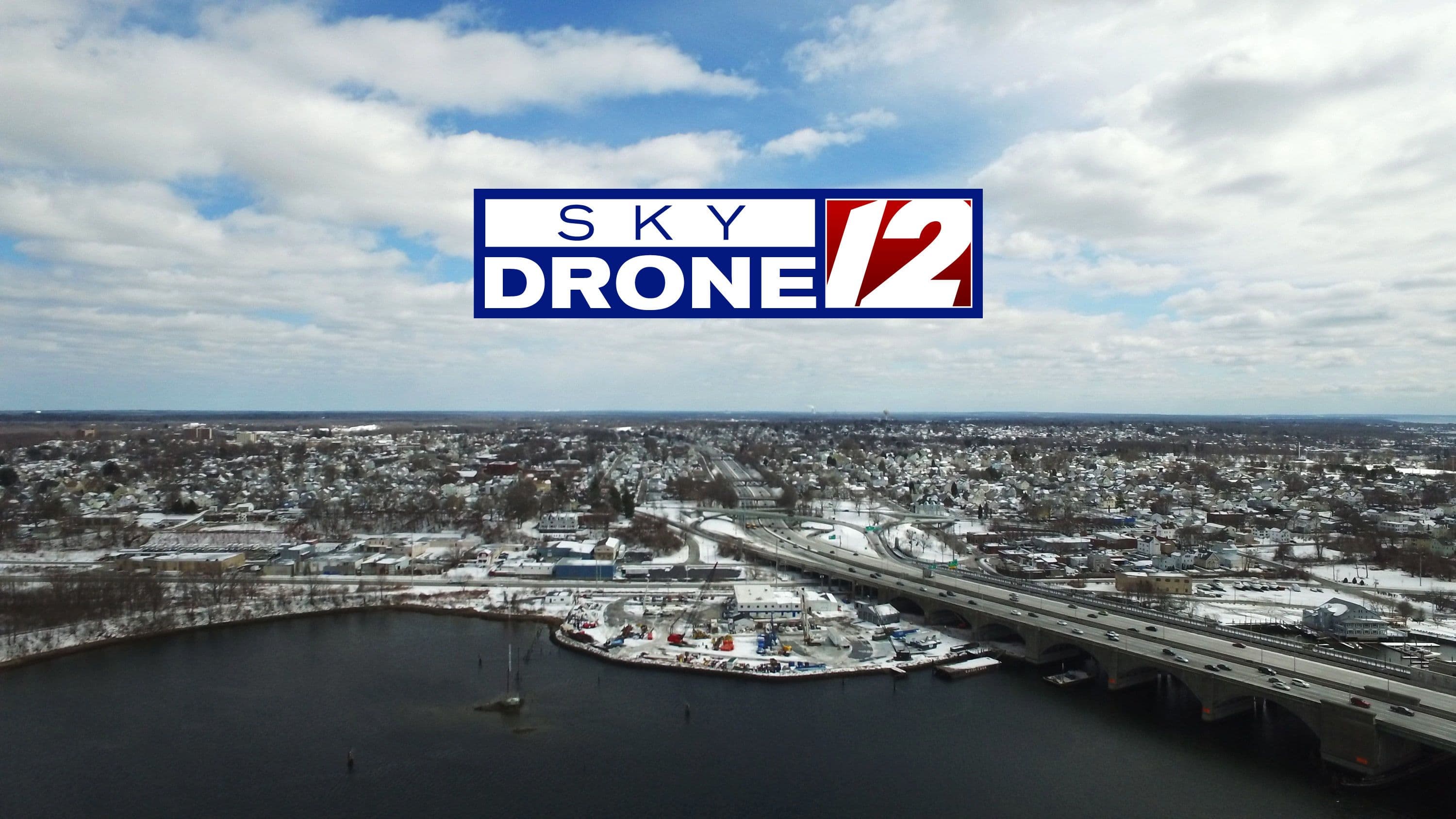 Aerial view of a snowy city with a bridge over water under a cloudy sky, representing atmospheric rhythms and life's navigation.