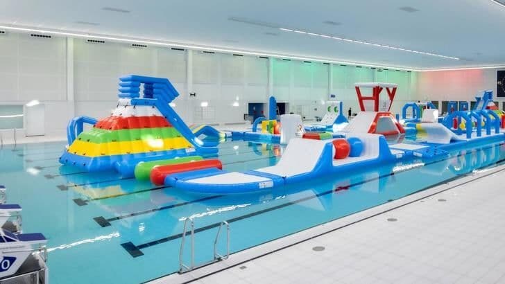 An indoor swimming pool with an inflatable obstacle course, representing ways to cool down and master the summer warmth.
