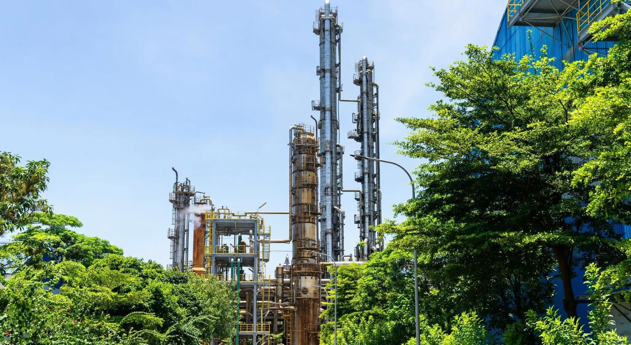 An industrial facility with tall towers surrounded by greenery, representing the infrastructure involved in agricultural input production.