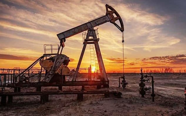 An industrial oil pump at sunset, illustrating the energy dependency of the global trade and agricultural logistics sectors.