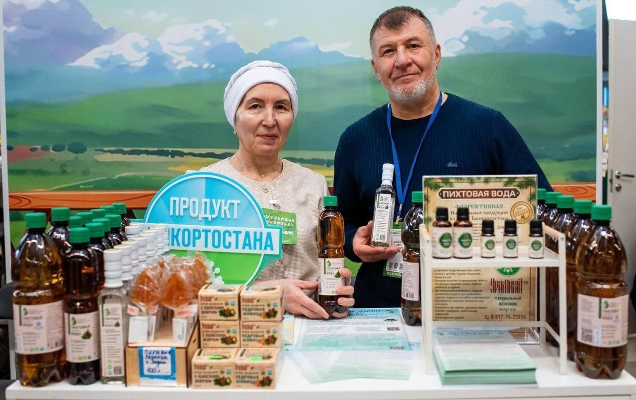 An older couple presenting bottles of natural fir water and other products at a market stall, highlighting local sourcing and sustainability.