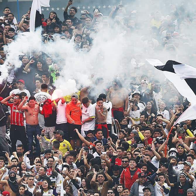 Apasionados aficionados de Rayo Vallecano animando en el Estadio de Vallecas, creando una atmósfera eléctrica.