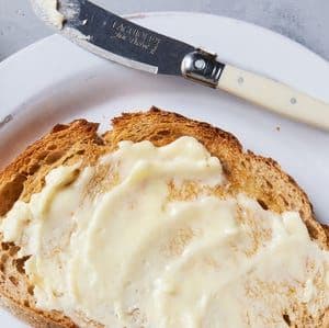Butter spread on toast with a knife, symbolizing food consumption