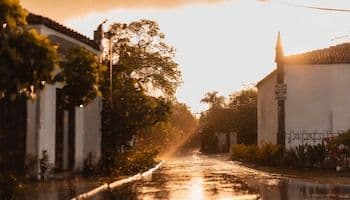 Calle mojada en un pueblo al atardecer, ilustrando el impacto de la lluvia en la vida diaria y la necesidad de adaptación.