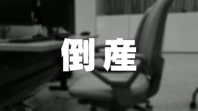 Caractères japonais '倒産' (Tōsan) signifiant 'faillite' ou 'banqueroute', sur un fond flou de bureau vide, symbolisant la fin de Shinminato Kamaboko.