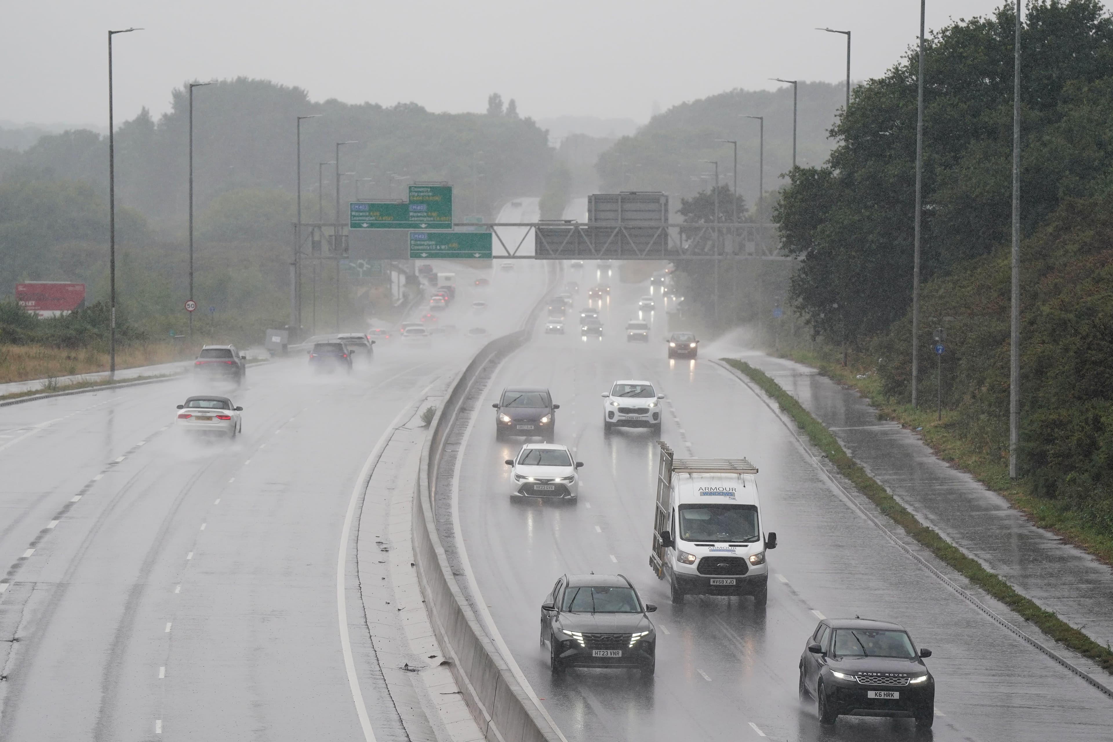 Cars driving on a heavily wet A46 motorway near Coventry, showing surface water runoff and challenging driving conditions during heavy rain.