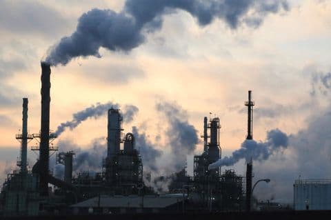 Cheminées industrielles fumantes, représentant l'impact environnemental potentiel de l'exploitation des hydrocarbures.